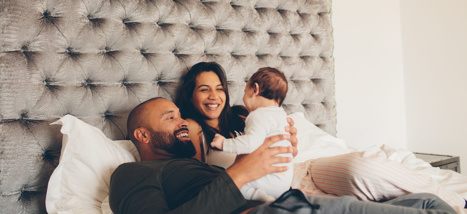 happy parents playing with baby - JoAnna Inks Sleep Solutions